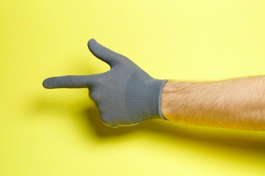 hand of a man, craftsman, gardener in a gray glove on a yellow background