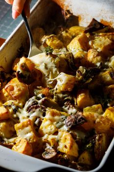 Girl picks up a spoonful of baked potatoes with mushrooms and cheese