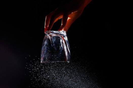 Black background on it is a close-up of a clean glass in a hand. Spray on a glass of water. Insulated glass