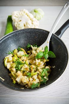 cauliflower fried with zucchini and vegetables in a pan with herbs