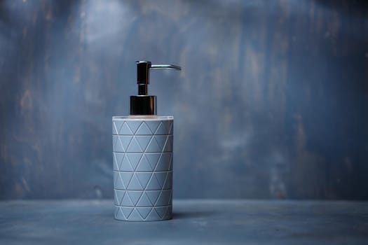 gray soap dispenser with a metal cap on a gray table