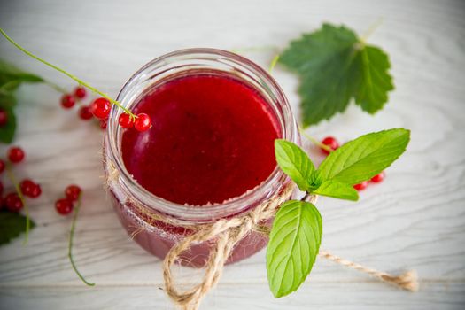 sweet summer jam from ripe red currants in a jar on a wooden table