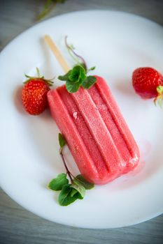 cooked homemade strawberry ice cream on a stick in a plate with strawberries