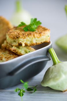 vegetable fried squash and zucchini cutlets in a ceramic form on a light wooden table