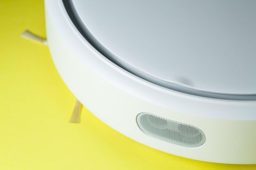 white robot cleaner for cleaning the house on a yellow background