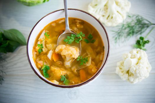 vegetable summer soup with cauliflower in a bowl on a light wooden table