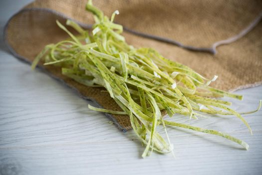 dried homemade green raw noodles with herbs on a wooden table