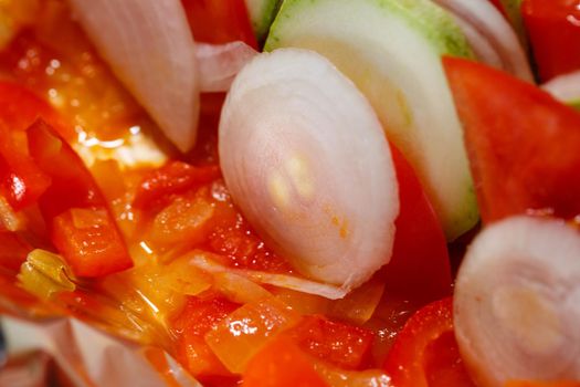 chopped vegetables tomatoes, zucchini, onions, peppers folded into a baking dish. Cooking ratatouille