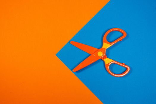 Children's plastic scissors for cutting paper figures on a colored background