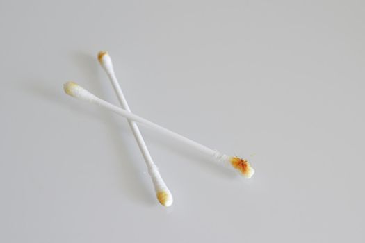 Two cotton swab used for cleaning ear with sulfur on white background, selective focus