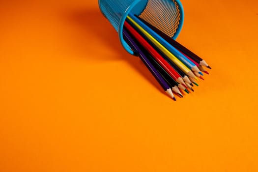 blue metal bucket with colored pencils for office on an orange background