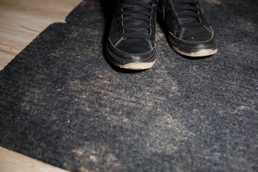 dirty shoes standing on a black carpet with a scattered swamp