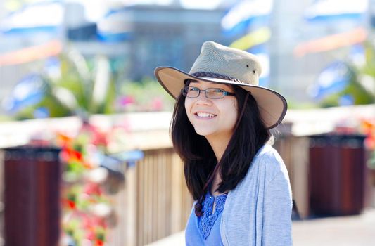 Young biracial teen girl smiling outdoors, sunny colorful background colors