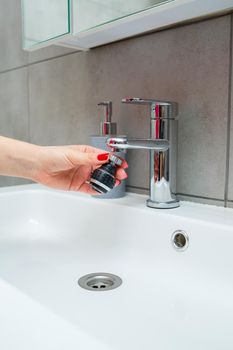 Rotary nozzle on the mixer to adjust the flow of water. White bathroom sink for washing hands