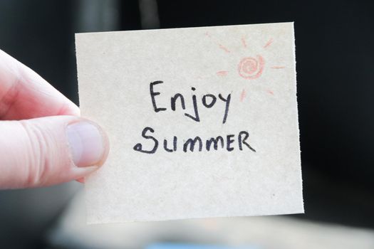 Enjoy summer. Creative concept. Hand holding a tag with the inscription. High quality photo