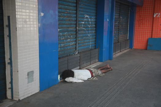 salvador, bahia, brazil - august 6, 2022: homeless man sleeping in front of a collection store in the city of Salvador.