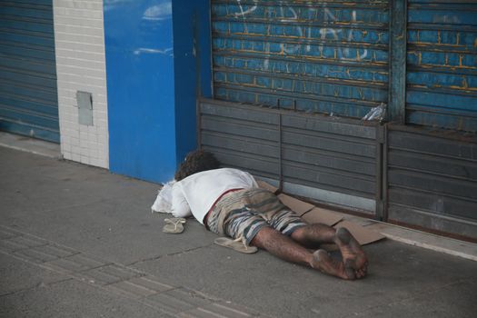 salvador, bahia, brazil - august 6, 2022: homeless man sleeping in front of a collection store in the city of Salvador.