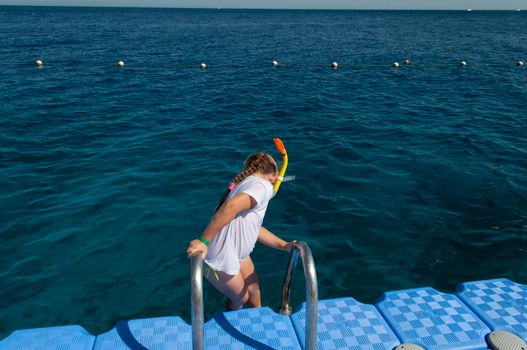 a little girl in a white t-shirt and a swimming mask, dives and swims in the salty Red Sea in Egypt, refreshes on a hot day, summer vacation adventure, summer vacation adventure. High quality photo
