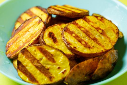 grilled potatoes until golden brown in a blue plate on a yellow background