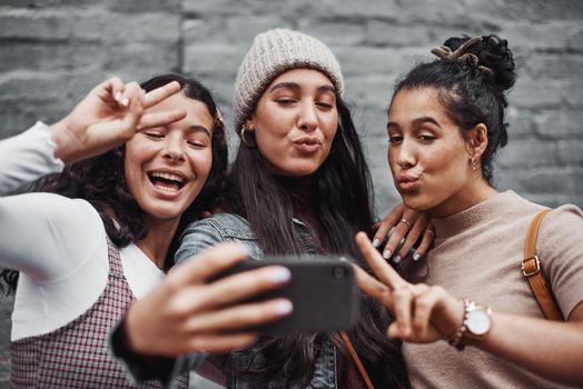 Sisters for life. Cropped portrait of an attractive group of sisters standing together and taking a selfie with a cellphone in the city