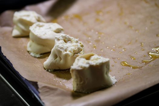 Baking domestic rolls with cheese. Putting cheese on dough for rolls