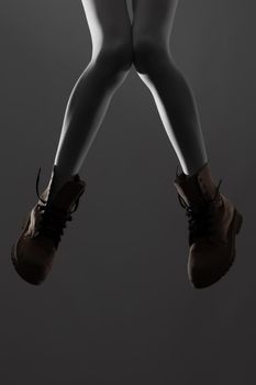 Sexy female legs with white leggings and waterproof boots. Side lit half silhouette.
