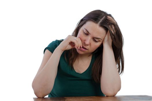 Young brunette long haired girl with finger in mouth looking at the floor thinking , isolated on white background