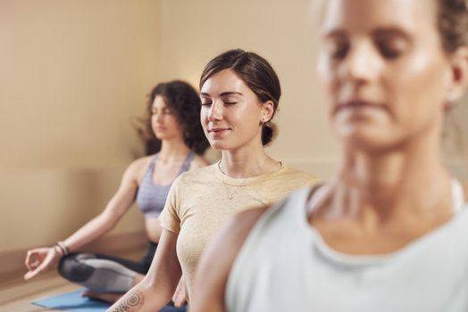 Yoga and meditation goes beyond the mat. a young group of women sitting together and meditating after an indoor yoga session