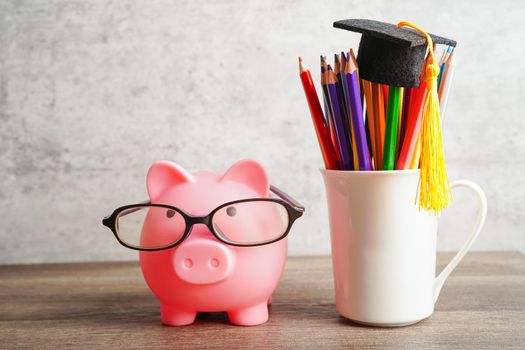 Pigging bank wearing eyeglass with coins and calculator saving bank education concept.