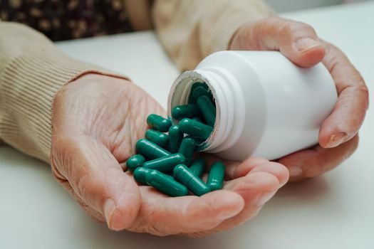 Asian elderly woman holding pill drug in hand, strong healthy medical concept.