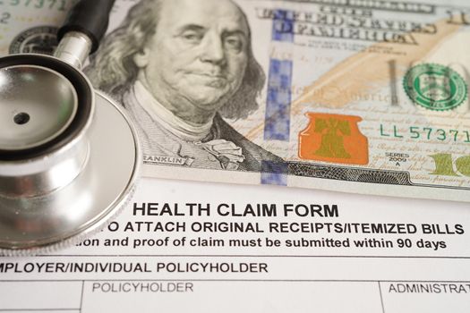 Health claim form with stethoscope and US dollar banknotes, insurance accident medical concept.