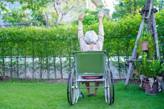 Asian elderly woman disability patient sitting on electric wheelchair in park, medical concept.