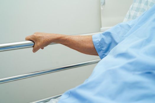 Asian elder senior woman patient holding bed rail while lie down with hope waiting her family in hospital.