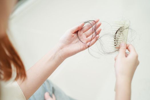 Asian woman have problem with long hair loss attach in her hand.