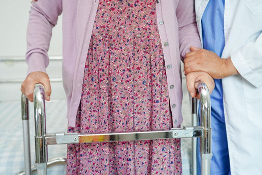 Doctor help Asian elderly woman disability patient walk with walker in nursing hospital, medical concept.