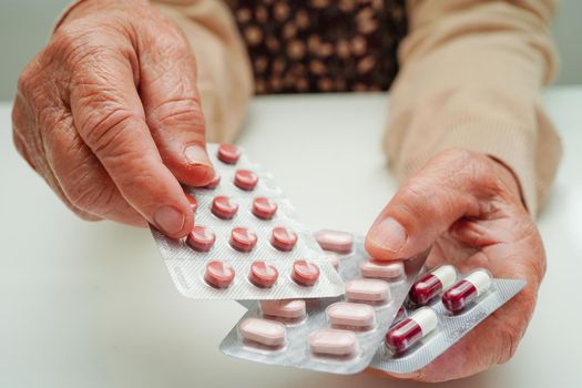 Asian elderly woman holding pill drug in hand, strong healthy medical concept. 