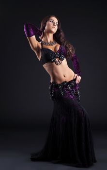 beauty girl in oriental purple arabic costume dance in dark
