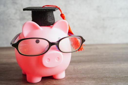 Pigging bank wearing eyeglass with coins and calculator saving bank education concept.