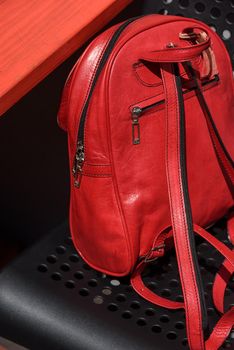 Red leather casual unisex backpack on a black chair. Outdoors photo