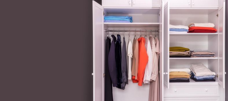 close-up of a white, open wardrobe with stylish women's items in one, light color scheme. Copy paste space for your design. The concept of organizing space, order, cleaning, reasonable consumption.