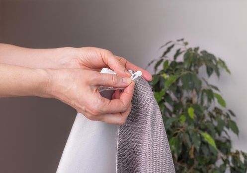 Close-up, the hands of a European woman show how to properly hem curtains, do embroidery, a professional decorate an apartment. Design for windows, fabrics and decoration