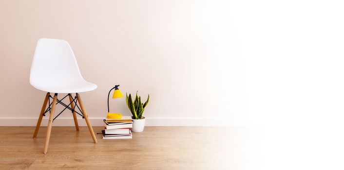 Long banner with blank white copy space for design. white chair, books nearby, table lamp, home flower. The concept of loneliness, the end of quarantine, online learning, end of lockdown