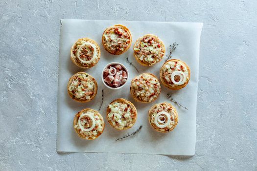 mini portions of flammekueche, or tarte flambee, french and german speciality, on the baking paper, top view