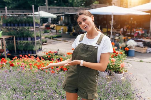Portrait of a beautiful young woman standing in front of a counter with different flowers in background