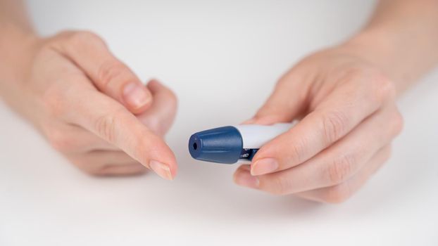 Caucasian woman doing a glucose test using a pen lancet