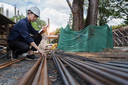 Engineers are checking the quality of deformed bars at the outdoors construction site.