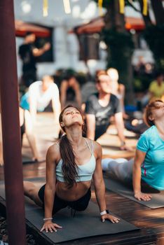 A woman does yoga together with her group in the open air. Healthy lifestyle concept