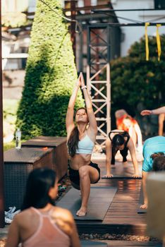 A woman does yoga together with her group in the open air. Healthy lifestyle concept