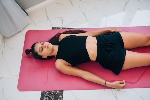 Young woman practicing in a yoga studio. Shavasana or corps pose is the end of a class or practice.