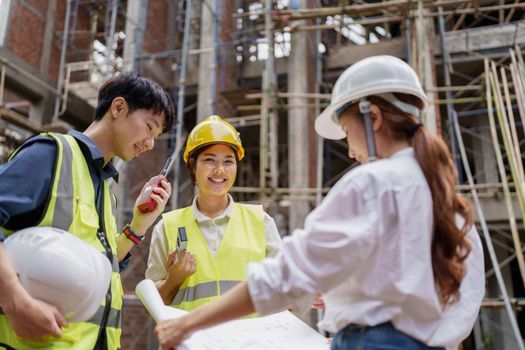 Structural engineer and architect discussing and working with blueprints at the outdoors construction site.